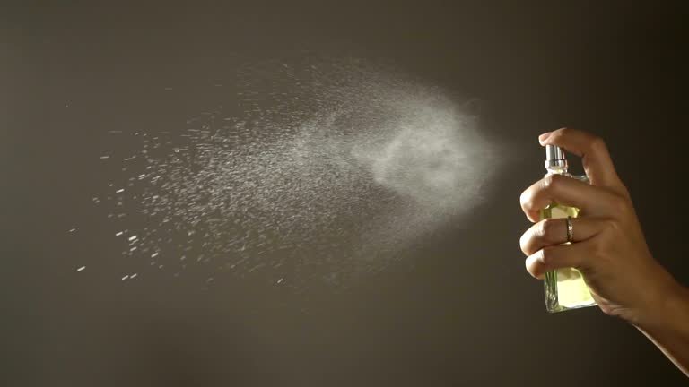 slow motion,woman spraying fragrance with scent particles.
